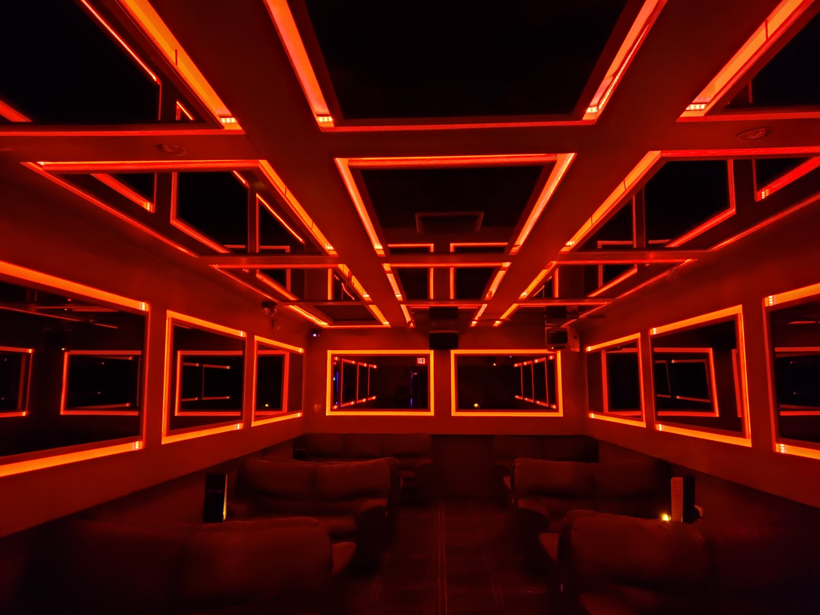 Custom LED lighting installation in a lounge with mirrored ceiling and walls, creating a dramatic red infinity effect.